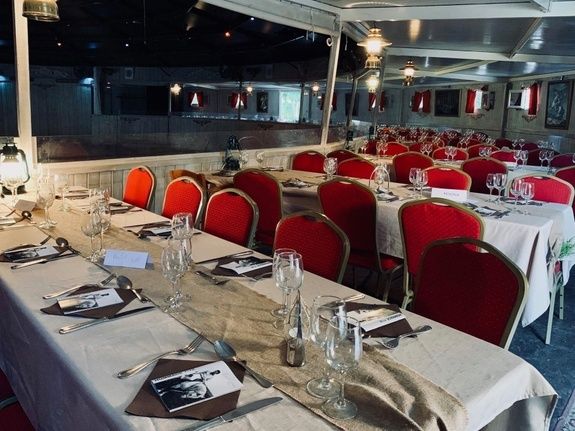 Tables dressées et fauteuils rouges autour de la piste du Cabaret équestre des Mylords, ambiance du repas. Photo du partenaire.